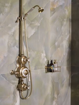 shower storage ideas brass wall hung rack on marble wall tiles by Drummonds