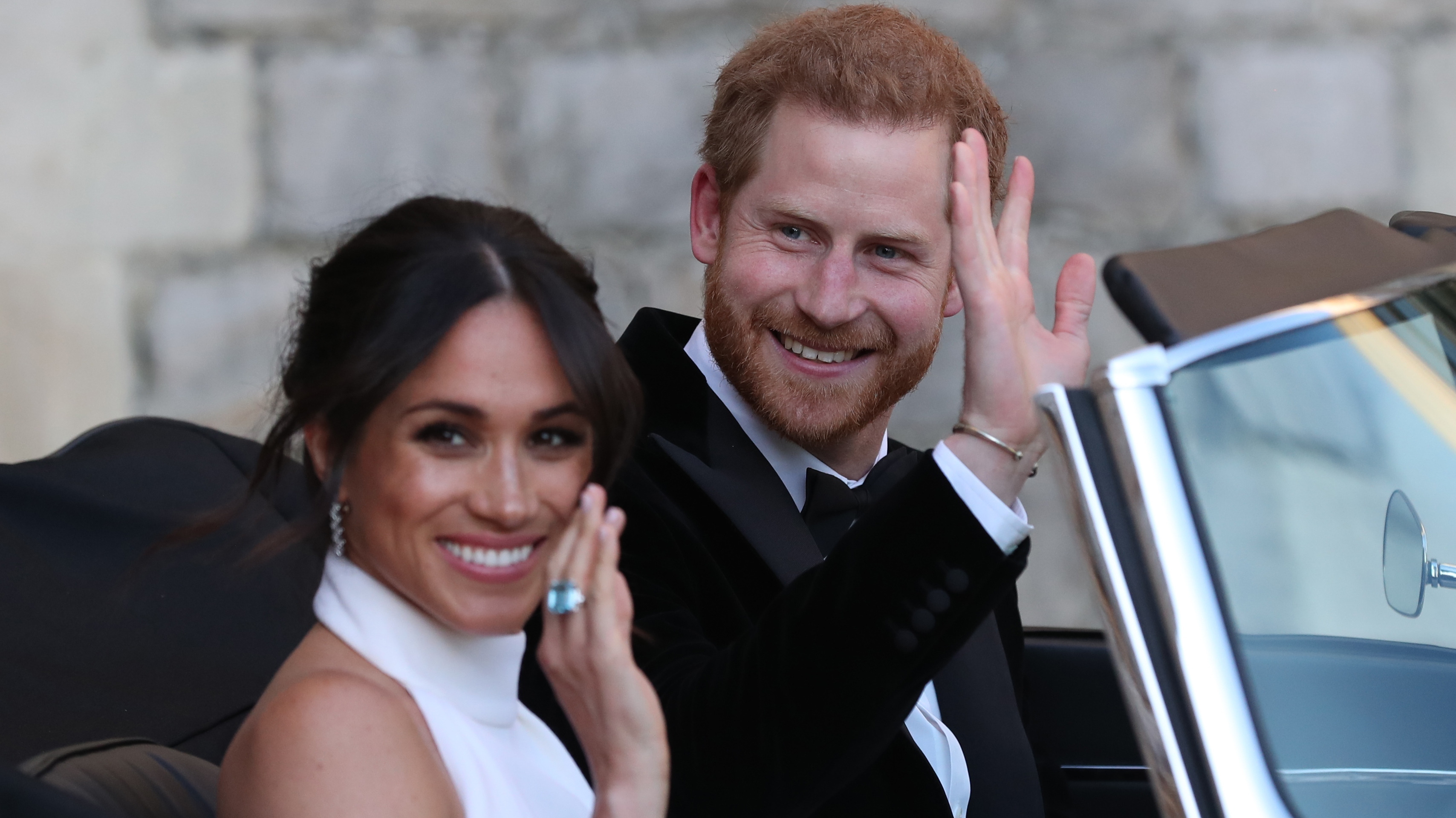 Duchess of Sussex and Prince Harry wave as they leave Windsor Castle after their wedding to attend an evening reception at Frogmore House on May 19, 2018