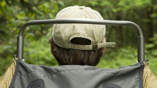 Rear view of a young man hiking with a external frame backpack in the Smoky Mountains on a summer day