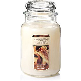 A large glass jar with a cream vanilla candle inside. A domed lid. A label that has ice cream cones on it. 