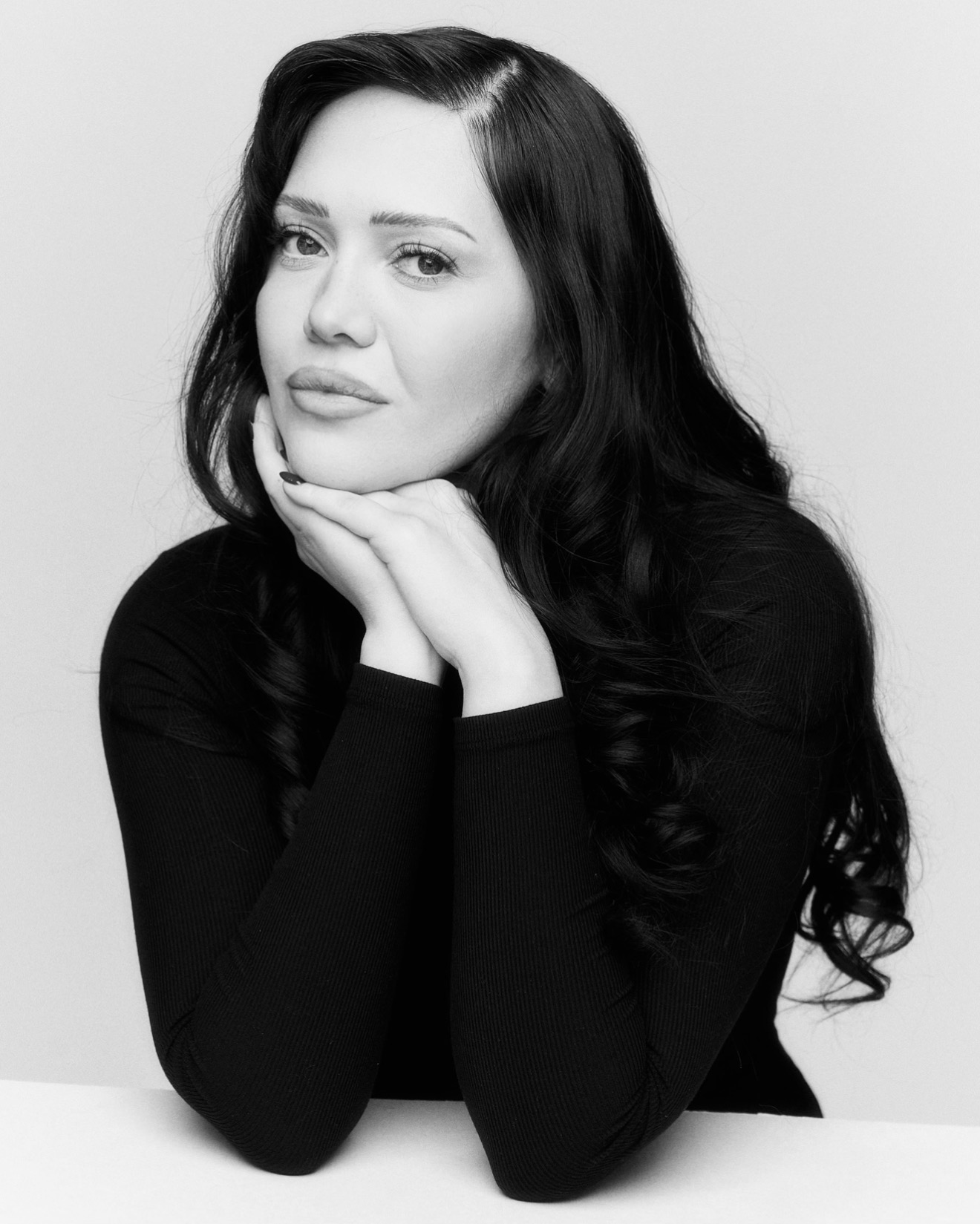 a black and white photo of a woman with long dark hair in a black turtleneck