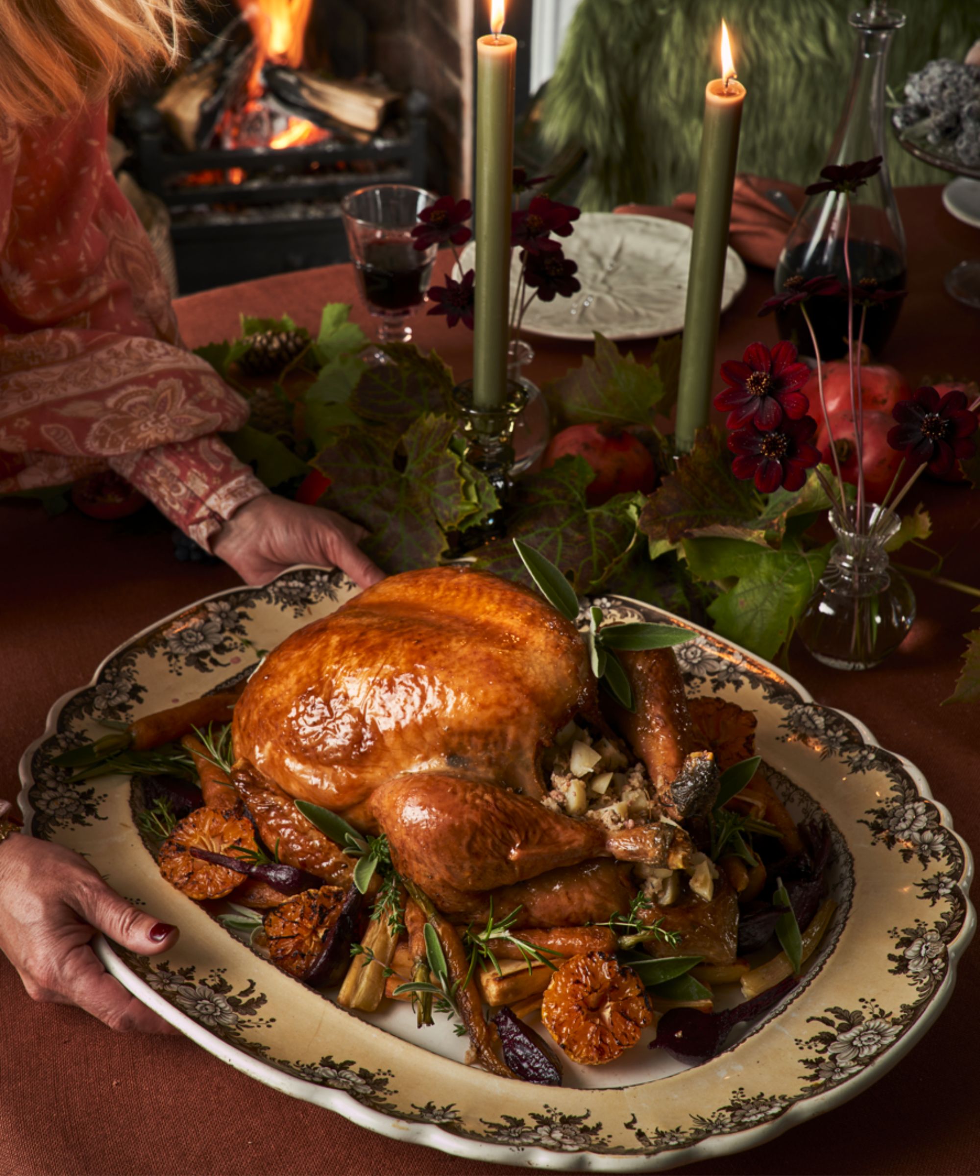 Roasted turkey on a platter being placed on a festive table