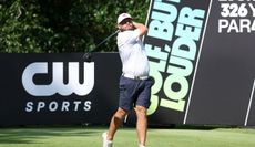 Tyrrell Hatton strikes a driver in front of a LIV Golf board