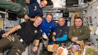 Crew members of Expedition 60 aboard the international Space Station float around ingredients of a meal they are preparing.