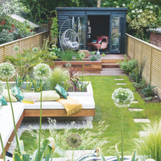  View down the garden with seating area and raised beds, wooden workshop at the end of the garden.