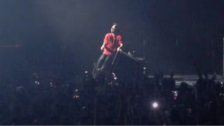Zach De La Rocha sits on stage
