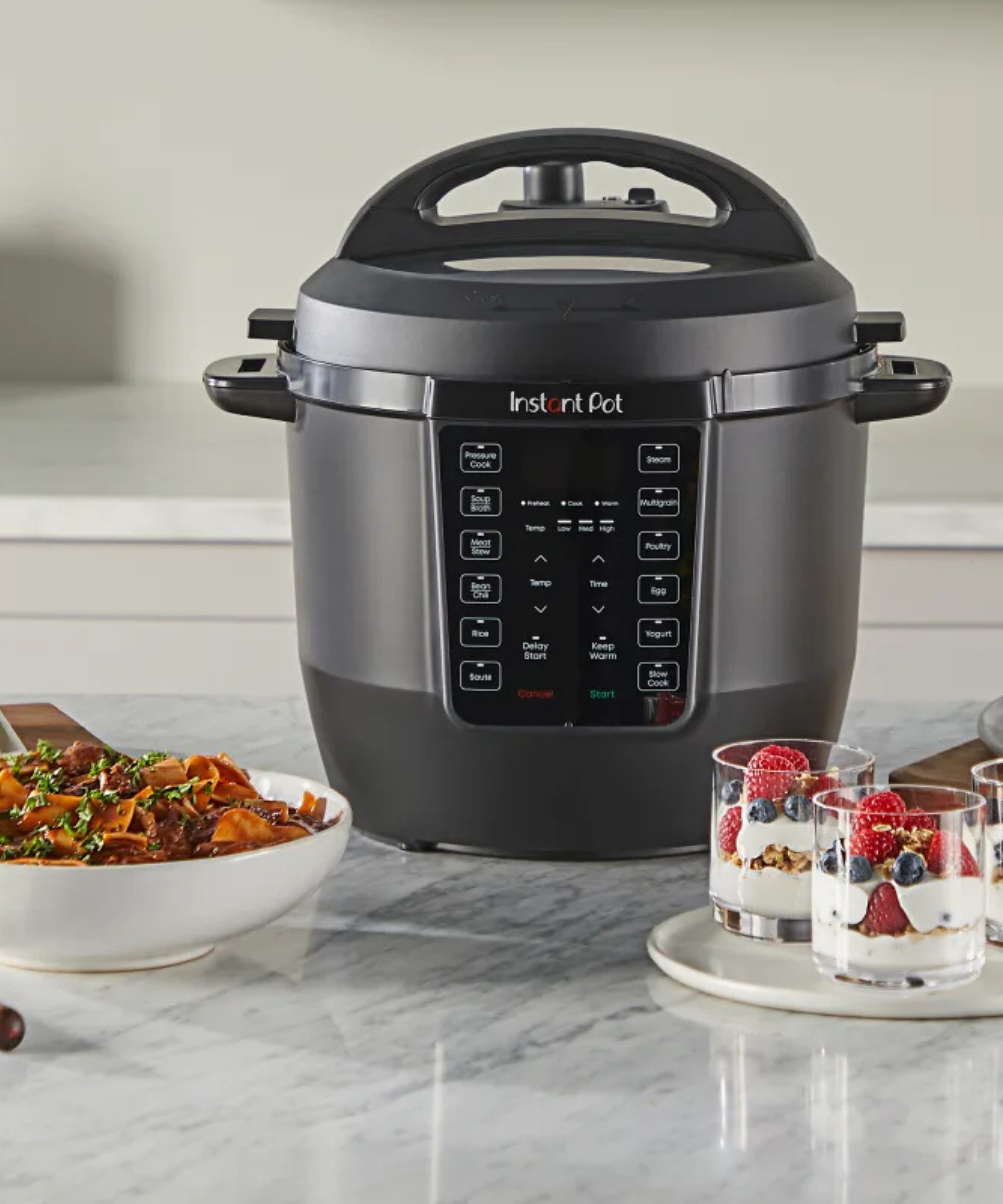 Instant Pot Rio on kitchen counter surrounded by beef pasta sauce and yogurt parfait desserts