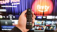 An Amazon Fire TV remote in front of a television running Fire TV.