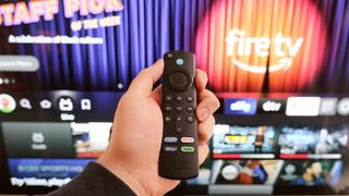 An Amazon Fire TV remote in front of a television running Fire TV.