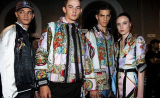 Male models wearing white and brightly patterned clothes from the Versace S/s 2018 collection