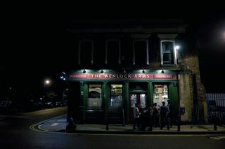 Exterior view of the front of the Wenlock Arms pub. Photographed are night with preople standing outside on the pavement