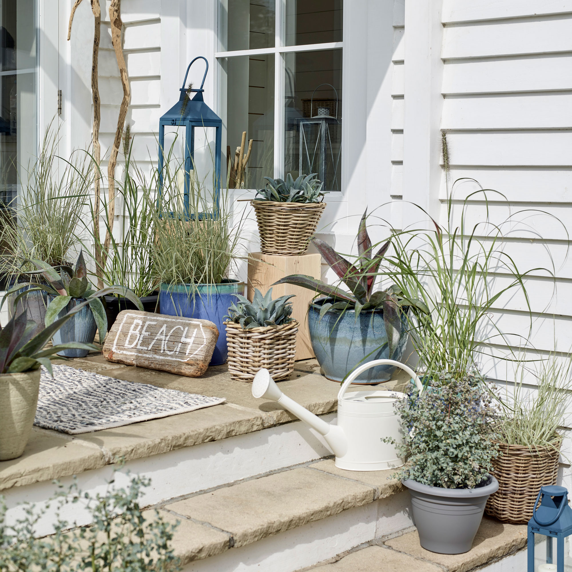 a set of stairs in a garden covered in planters and pots in blue, white and grey