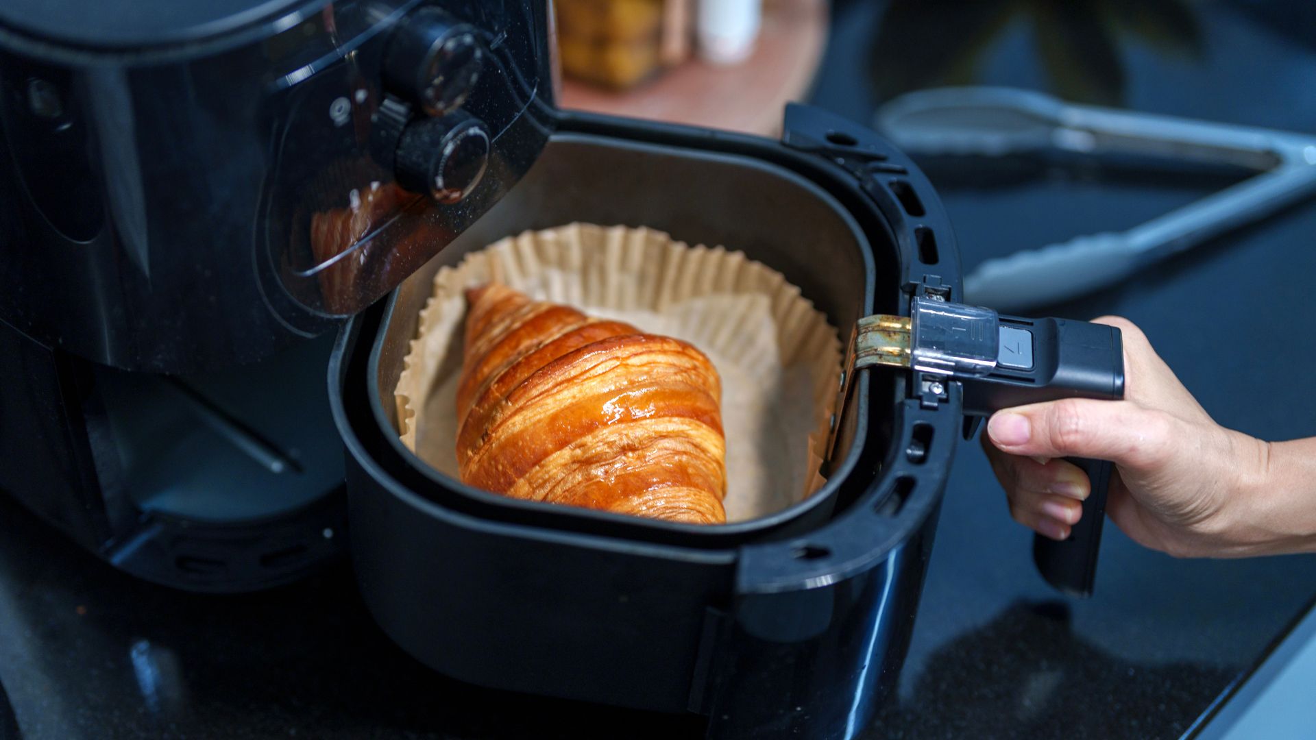 parchment liner in air fryer with croissant being reheated