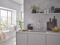 A kitchen with a grey countertop and chrome mixer tap 