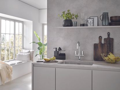 A kitchen with a grey countertop and chrome mixer tap 