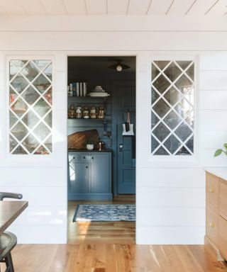 Vintage windows looking into blue kitchen with shelving