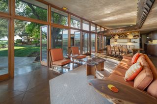 A living room with banquette seating, mid-Century furniture and leather chairs