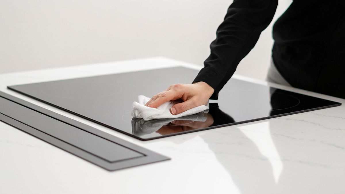 Woman cleaning an ceramic induction cooktop