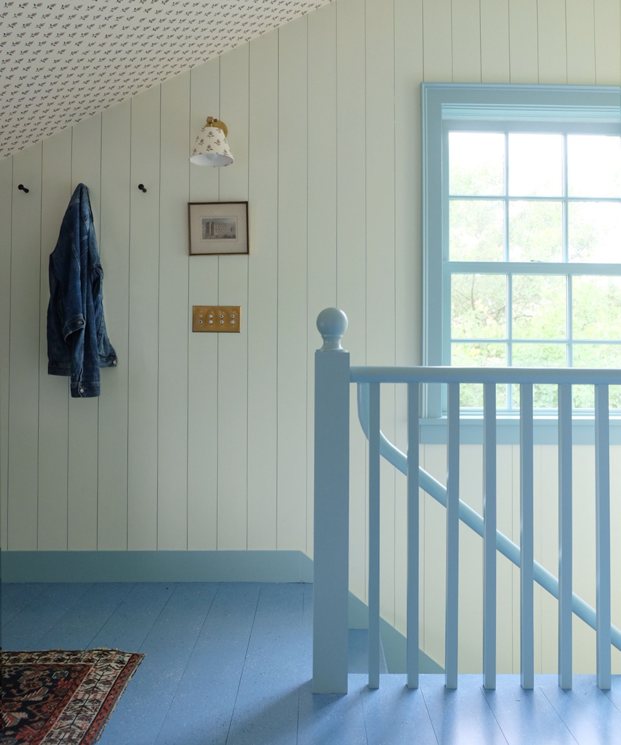 a light and bright stairway with paneled walls, a floral ditsy wallpapered ceiling and blue painted floor, staircase and trim