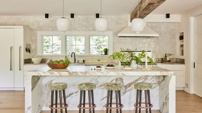 kitchen with marble faced island and wooden beam with white lustre tile backsplash