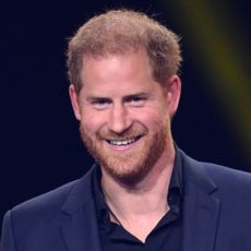 Prince Harry smiles while wearing a navy suit