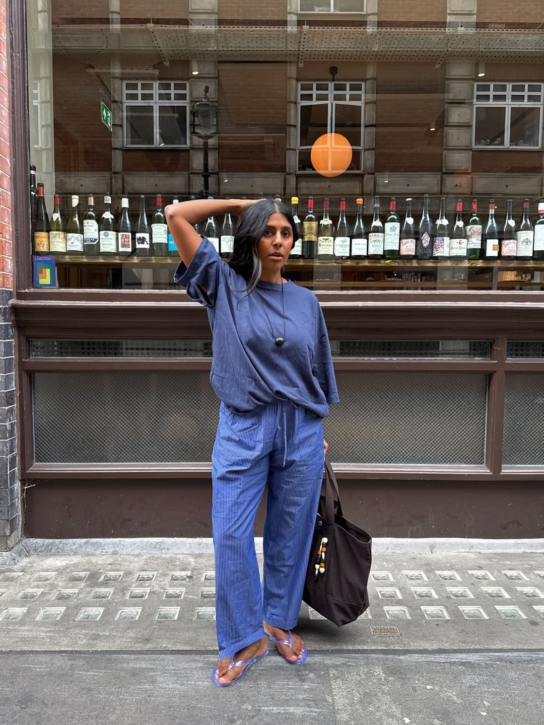@monikh wears blue linen trousers, blue T-shirt, flip flops and cord necklace