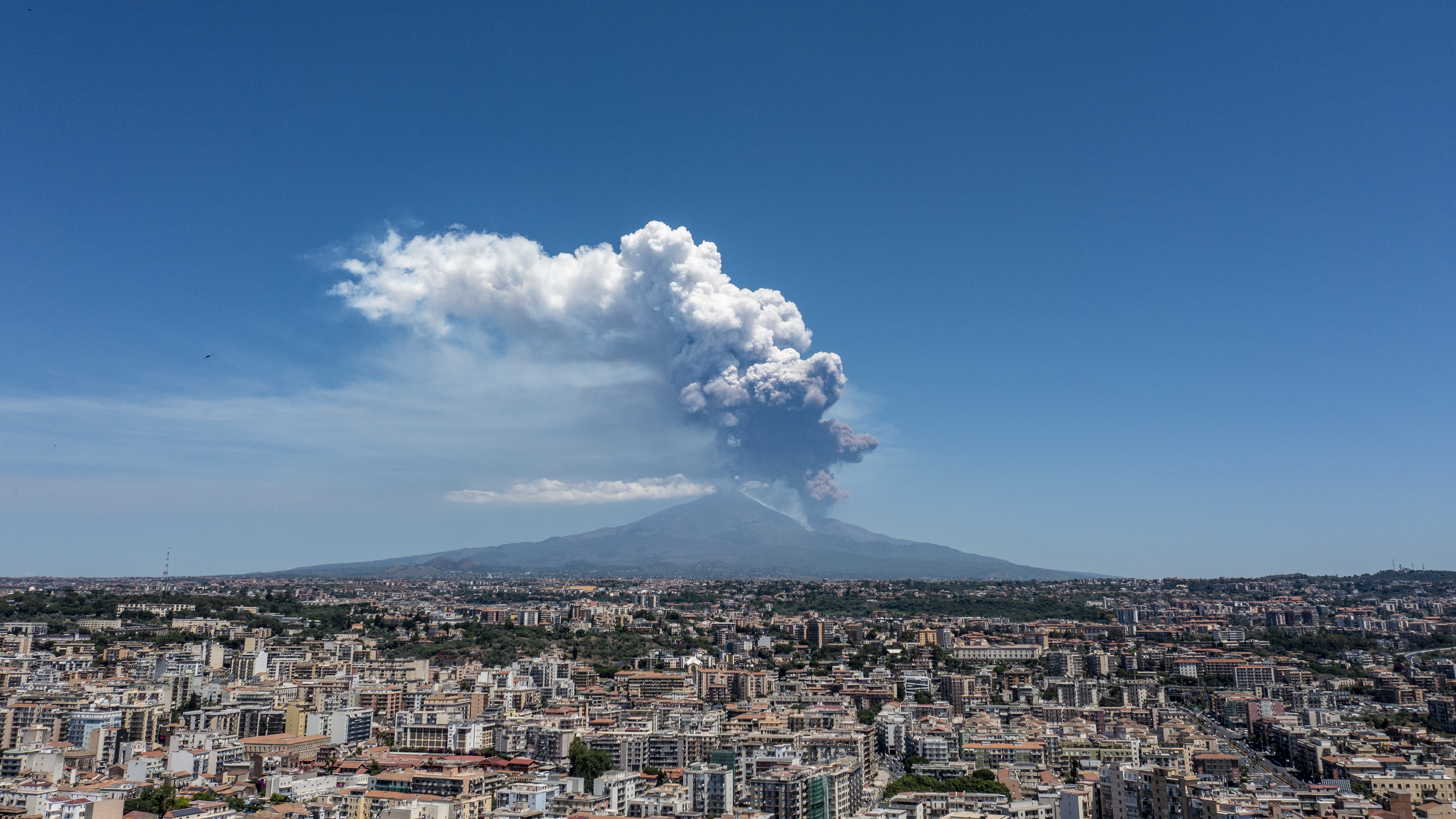 A photograph of the Mount Etna eruption in the distance behind Catania.