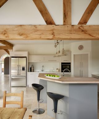 Sociable kitchen island in rustic scheme with bar stools, and exposed wooden beams