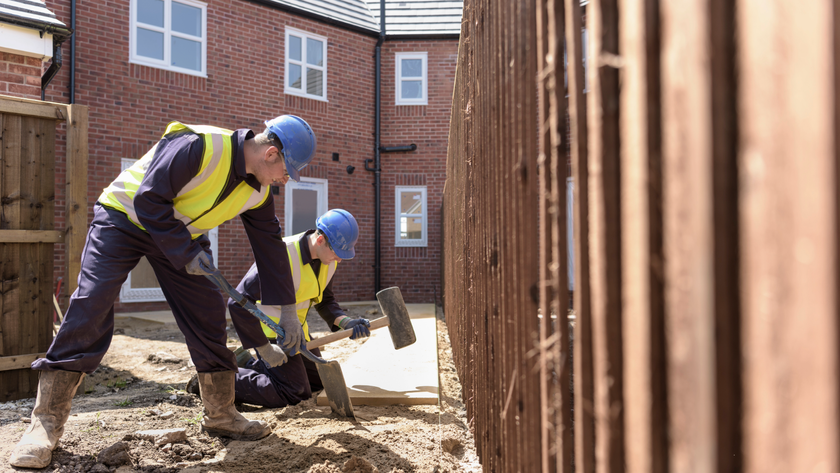 Two builders digging outside a house