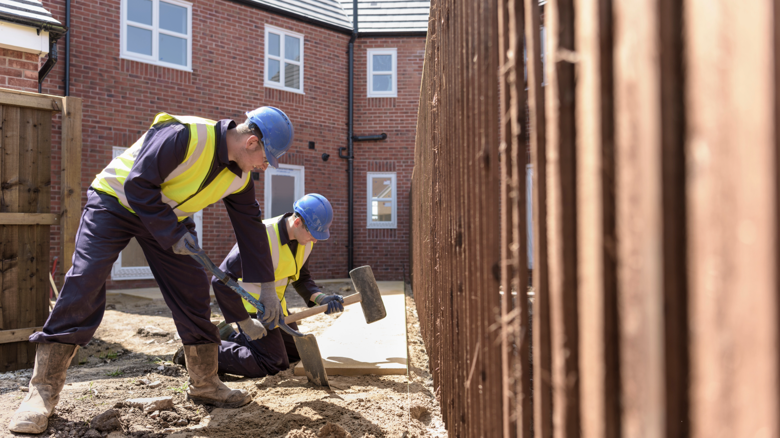 Two builders digging outside a house