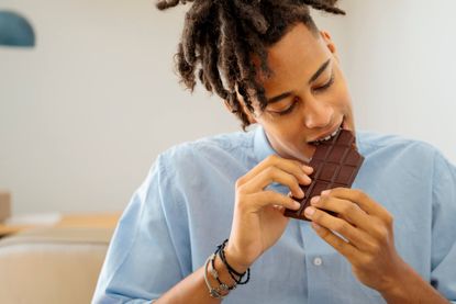 A man is biting into a large chocolate bar.