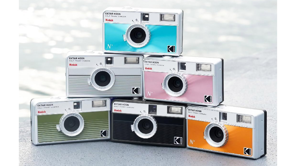 A lifestyle picture of six Kodak Ektar H35N cameras stacked up like a pyramid and each in different colors