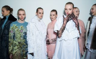 a line of female models wearing varying types of dress including a white ruffled one