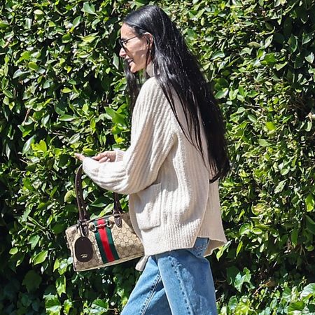 Demi moore wears a sweater, gucci bag, and jeans.