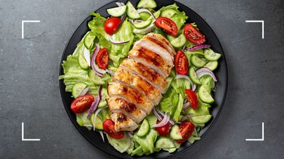 Chicken salad, grilled chicken breast on bed of green lettuce and red tomatoes, as an example of what to eat on the 5:2 diet