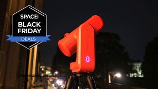 A red Unistellar Odyssey Pro pointing at the sky in a city at nighttime with a black Space.com Black Friday deals badge in the upper left corner.