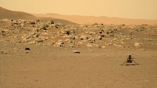 small helicopter sits in front of ridge with numerous martian rocks on it. peach sky and hills are far in behind