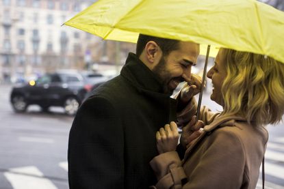 Happy business couple under umbrella in the city