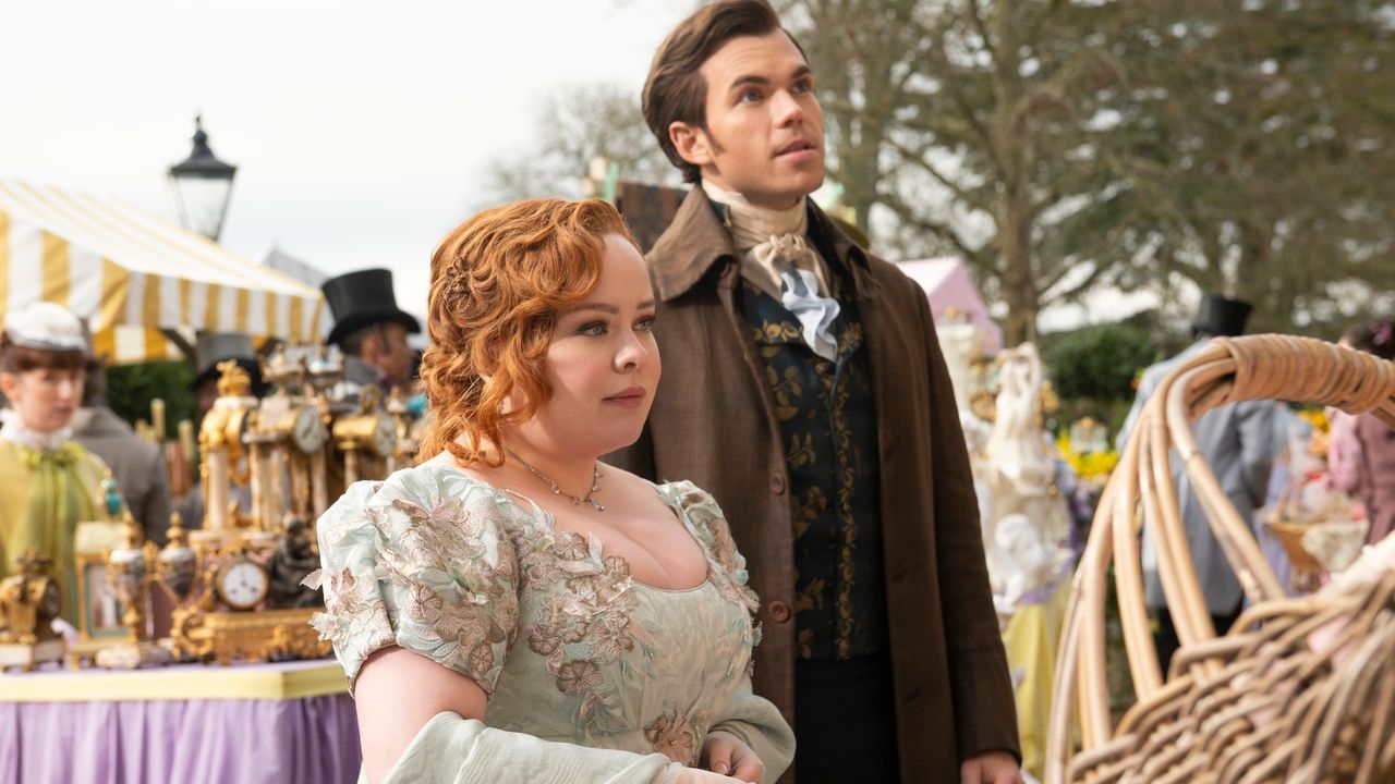 nicola coughlan as penelope featherington and luke newton as colin bridgerton, standing apart from the crowd at an outdoor event, in &#039;bridgerton&#039; season 3