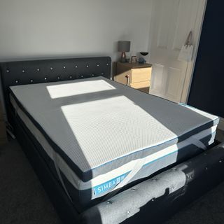 The Simba Hybrid mattress topper on a grey upholsterd bed in white bedroom