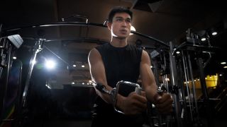 Man performs the cross-over chest exercise in the gym