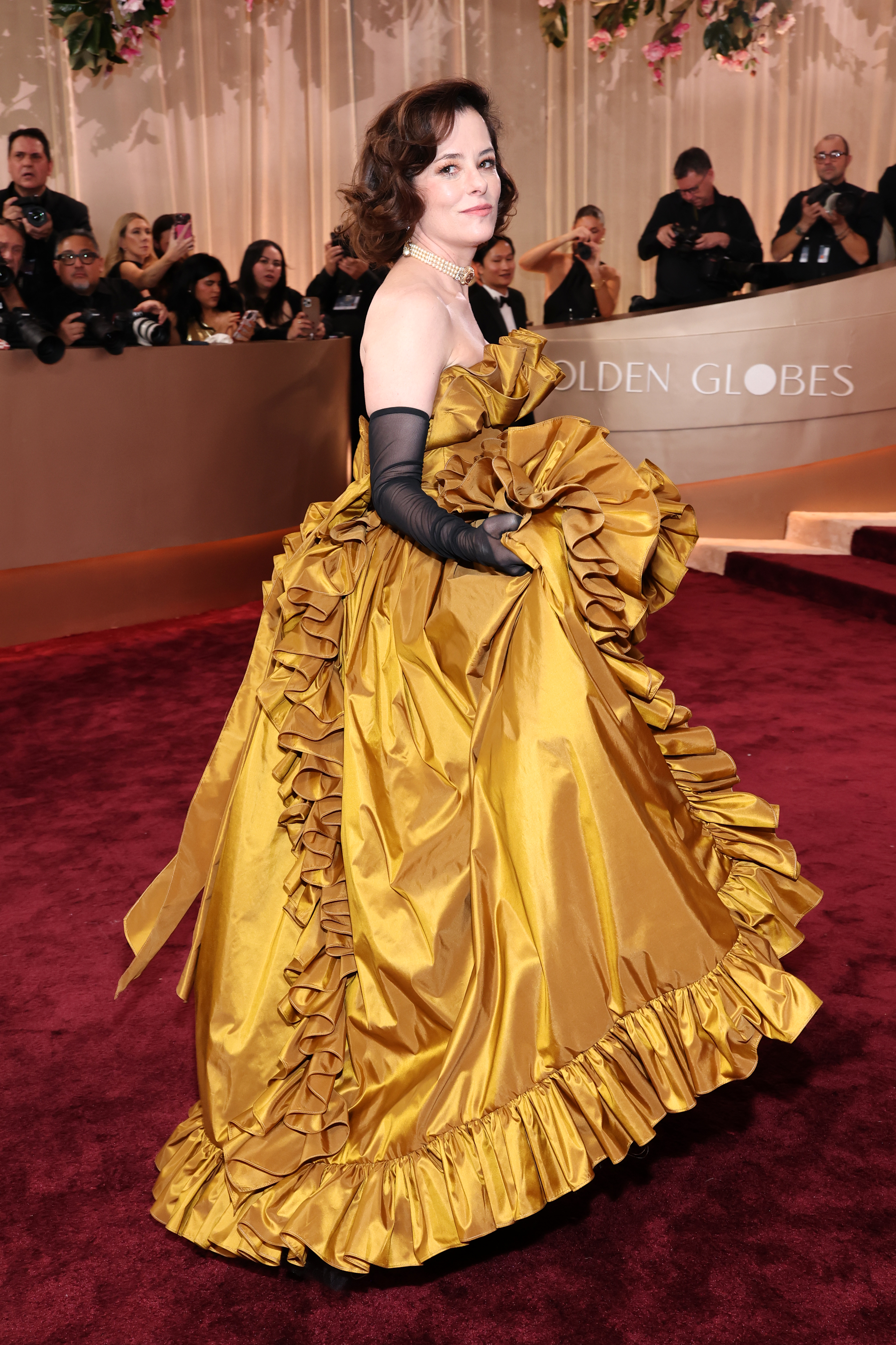 a white woman wears a golden yellow gown on the red carpet