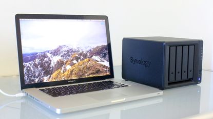 Best NAS drives. Apple MacBook Laptop on desk with Synology NAS drive