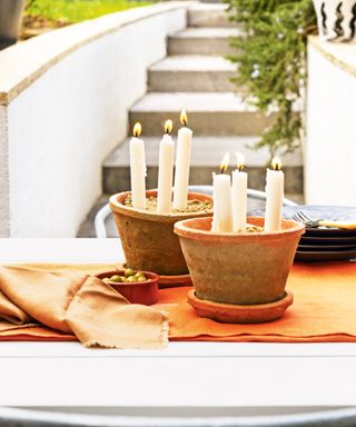 A simple table centrepiece with candles positioned in terracotta bowls
