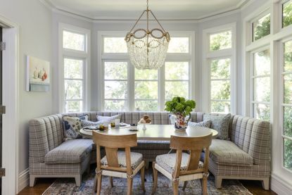 dining table with bench seats and wooden chairs in bay window with chandelier above
