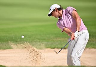 Jarvis hits a bunker shot with a pink shirt