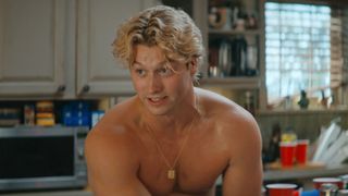 Stephen Kalyn shirtless while sitting in the kitchen of the Off Campus house. 
