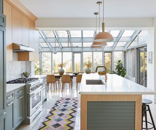 Solarium kitchen with green and wood cabinetry and a patterned runner