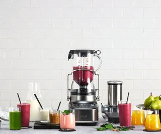 The Bluicer Blender and juicer on a countertop surrounded by fruit and vegetables