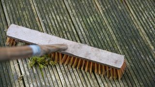 person brushing a wooden decking with a broom